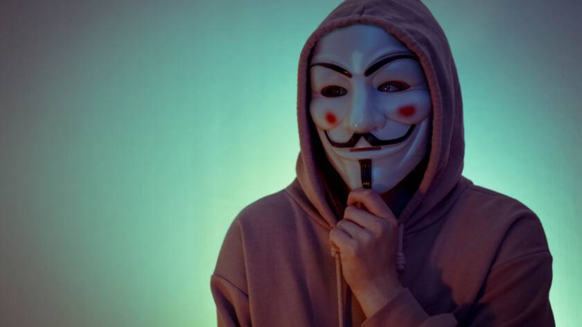 Portrait of a person wearing a hoodie and the Guy Fawkes mask