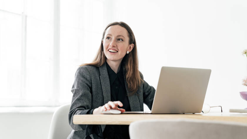 young female financier uses a laptop in formal attire. An online website for analytics